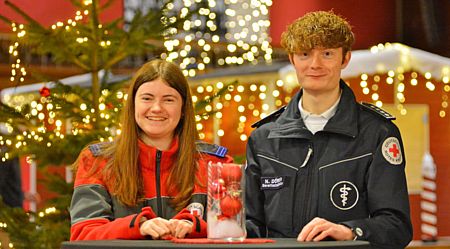 Das Foto zeigt Bereitschaftsleiter Niklas Dörner und Blutspendebeauftragte Luisa Sophie Dörner in weihnachtlicher Atmosphäre im Interview mit Rainer Schmitt (Sieger Zeitung) zum Thema der Weihnachtsblutspende.