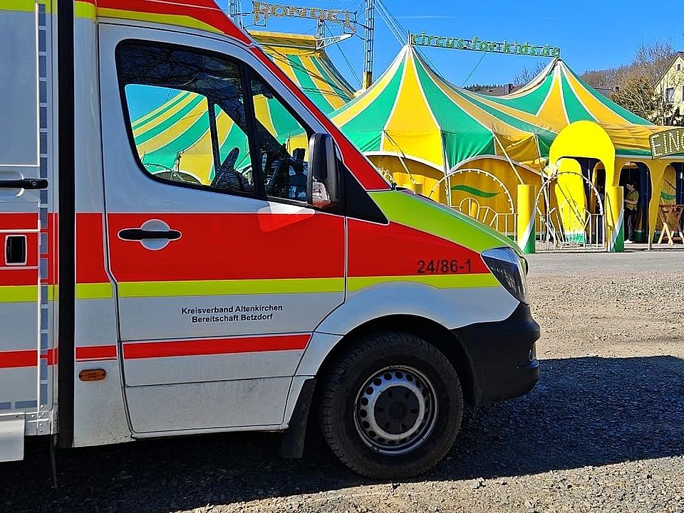 Abgebildet ist der Betzdorfer RTW, sowie im Hintergrund ein Zirkuszelt, anlässlich des Schulzirkus in Betzdorf