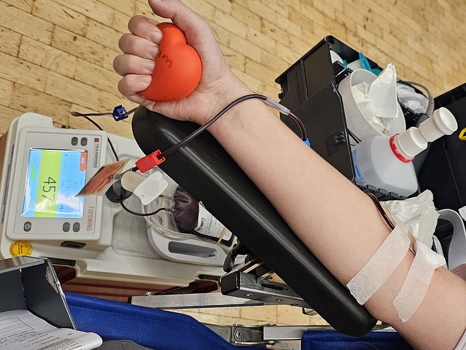 Abgebildet ist der Arm einer Helferin, während der Blutspende.