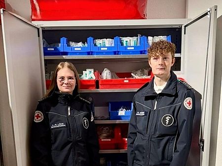 Bereitschaftsleiterin Lara Sophie Lück und Bereitschaftsleiter Niklas Dörner informieren über neuen Materialschrank