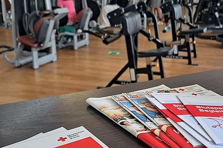 Flyer der Blutspende auf dem Tresen des Atlas Sport Betzdorf, im Hintergrund Sportgeräte