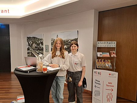 Blutspende_11.03.2026_Begruessung Zwei Helferinnen, eingesetzt als Blutspendelotsen, bei der Begrüßung der Spender.